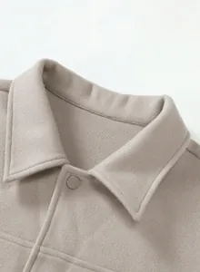 Close-up detail showing the collar and snap button of a beige men's woolen jacket outerwear