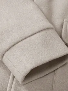 Close-up of beige woolen jacket cuff detail with neat stitching and felt texture
