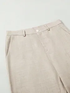 Detail of beige business suit trousers waist showing fabric texture and pocket.
