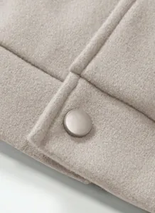 Detailed close-up of beige woolen jacket showing high-quality fabric texture and button