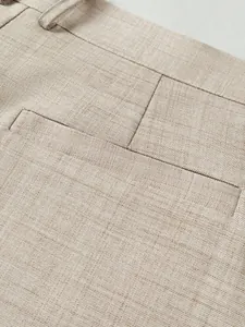 Macro view of light beige men's formal suit trouser fabric showing fine woven texture