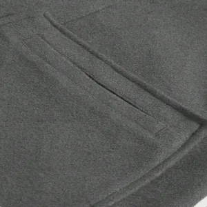 Close-up detail of a dark grey wool coat welt pocket showing premium fabric texture
