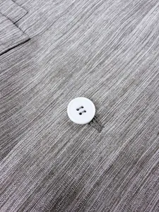 Detalle de cerca de tela texturizada gris y botón blanco en un traje de negocios para hombre