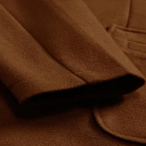 Close-up of the brown wool coat sleeve showing high-quality fabric texture and stitching.