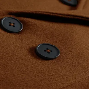 Macro close-up detail showing black buttons on premium brown wool overcoat fabric texture
