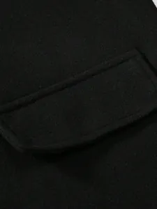 Vue rapprochée d'un rabat de poche de manteau en laine noire avec texture de tissu de qualité