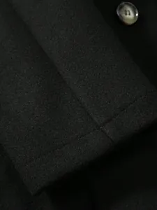 Gros plan détaillé de la texture du tissu et du bouton d'un manteau en laine noir pour homme