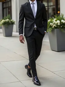 Full body detail of a man walking in a black slim-fit business suit with grey tie
