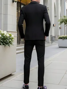 Back view of a man in a professional slim fit black business suit on a street.