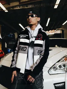 Close-up detail of a men's racing style streetwear jacket worn by a model in a garage.