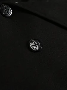 Close-up detail of anchor-patterned black buttons on a premium wool coat fabric texture
