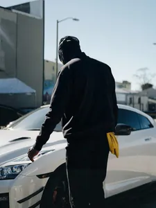 Back view of a black racing-style streetwear jacket for men in an urban outdoor setting