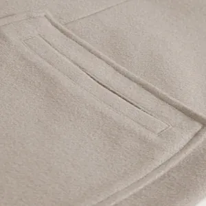 Detailed close-up showing the pocket and fine stitching of a beige wool overcoat for men