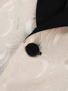 Detailed close-up of elegant ivory jacquard fabric and black button on men's tuxedo jacket