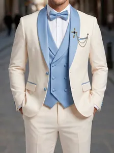 Detalle de un traje de tres piezas crema y azul claro con accesorio de broche de cruz