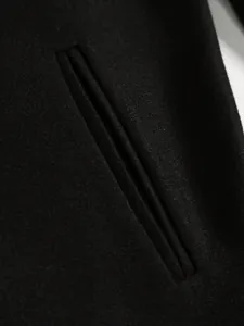 Close-up detail of a jetted pocket on a classic black wool blend men's business coat