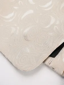 Close-up detail of elegant beige rose jacquard fabric texture on a men's tuxedo suit jacket.