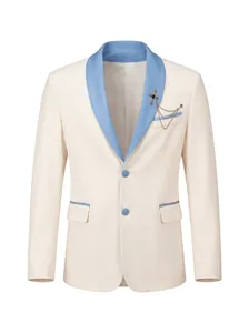 Detalle de blazer de gala para hombre en crema con solapa chal azul y broche ornamentado.