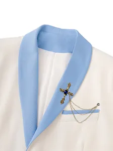 Primer plano de un broche de cruz dorada vintage con gema azul en la solapa de un traje