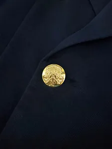 Close-up detail of a gold embossed crest button on a navy blue business suit jacket
