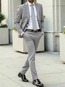 Full-body view of a man in a tailored light gray business suit on a city sidewalk.