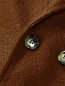 Vue macro détaillée des boutons élégants sur un manteau en laine marron pour hommes.