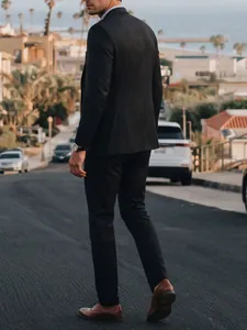 Full rear view of a gentleman in a black slim-fit business suit set on an urban street