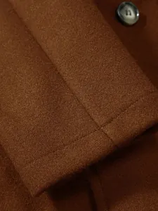 Vue macro détaillée montrant la texture du tissu en laine marron et le bouton de ce manteau