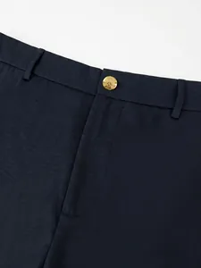 Close-up detail of navy blue business suit trousers featuring an ornate golden button