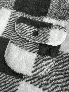 Close-up of black and white plaid plush jacket showing pocket detail and button