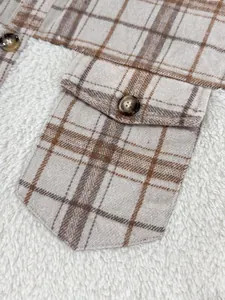 Close-up detail of a plaid and fleece patchwork street jacket showing a buttoned pocket