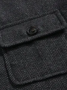 Macro detail of charcoal herringbone fabric on men's business vest with a button