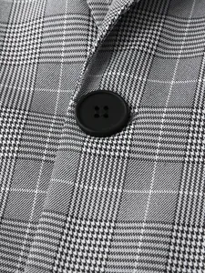 Close-up of black button and grey glen plaid fabric texture on men's suit jacket