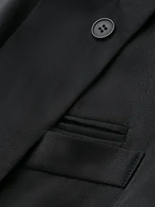 Macro detail of black men's suit jacket showing twill fabric texture and matching button.