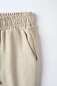 Close-up of the elastic waistband and side pocket of men's beige casual pants.