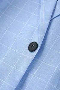 Detaillierte Nahaufnahme von hellblauem Plaid-Blazer-Stoff und einem Knopf detail