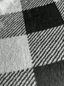 Detailed macro view showing the soft black and grey plaid plush fleece fabric texture.