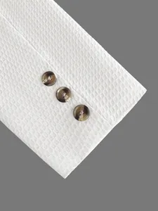 Macro-opname van een witte getextureerde pakmanchet met drie donkere marmeren knopen