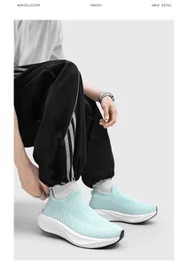 Detail view of light blue fly-knit slip-on sneakers worn with black sports pants