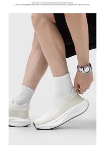 Macro view of white fly-knit slip-on sneakers with thick soles worn by a model