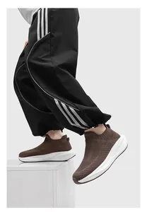 Close-up detail of brown mesh knit sock sneakers with thick white soles worn by model.