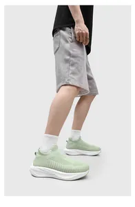 Detail view of light green fly-knit slip-on sock shoes with thick white soles.