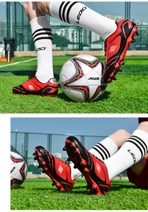 Detail von roten und schwarzen Kinder-Fußballschuhen mit AG-Stollen auf dem Rasen