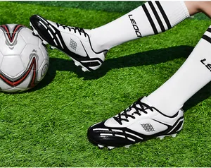 Nahaufnahme von schwarz-weißen AG/TF Fußballschuhen auf grünem Kunstrasenplatz
