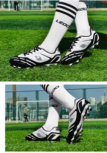 Detaillierte Ansicht von weiß-schwarzen Profi-Fußballschuhen auf grünem Kunstrasen