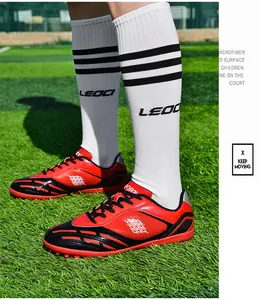 Rote und schwarze TF-Turf-Fußballschuhe für Kinder und Jugendliche auf Kunstrasen