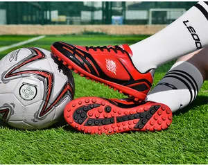 Detailansicht der rot-schwarzen Fußballschuhe mit TF-Stollen auf einem Kunstrasenplatz