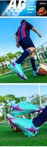 Close-up of cyan and purple soccer shoes with AG studs on professional turf