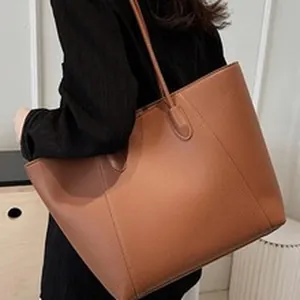 Close-up detail of a large brown matte tote bag carried as a stylish commuter accessory