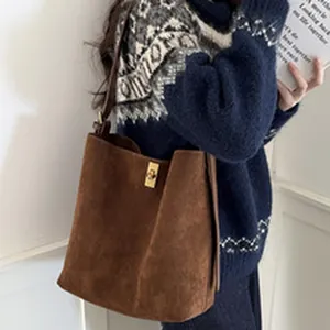 Detailed view of a retro brown suede tote bag featuring an elegant gold metal clasp